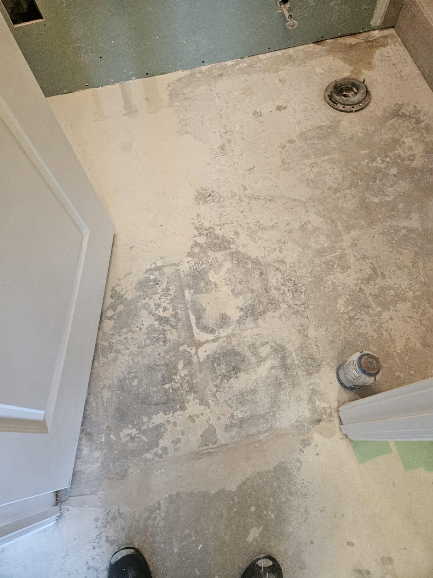 The same bathroom floor before, stripped to a stained subfloor.
