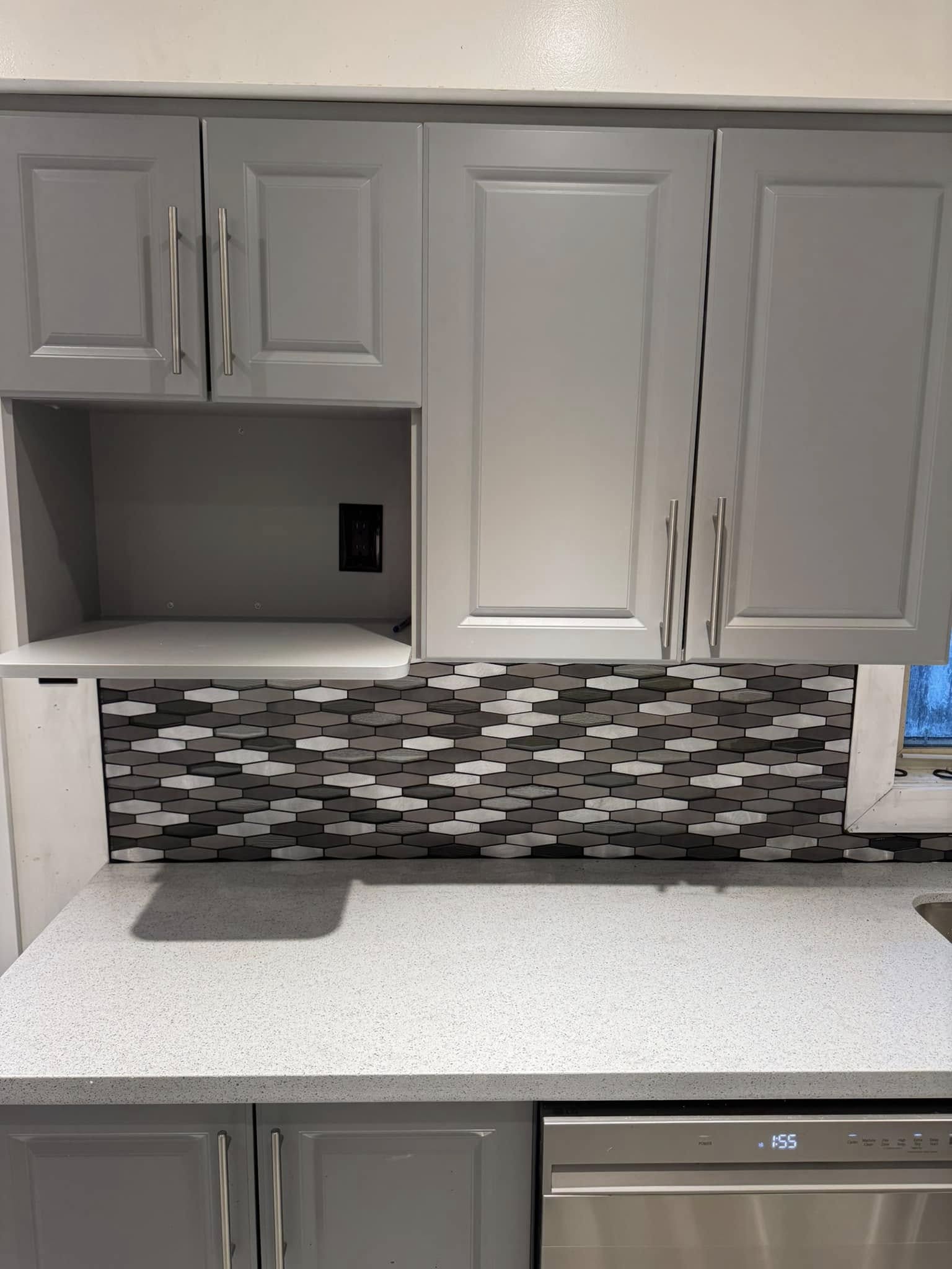 Kitchen with grey cabinets and a mosaic tile backsplash.
